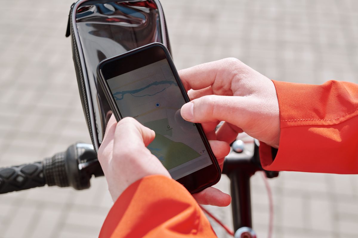 Cyclist checking a GPS navigation app on a phone mounted to the handlebar